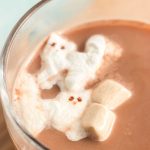 a top view of a mug of hot chocolate with two cat marshmallows on it