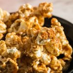 caramel covered popcorn in a black bowl