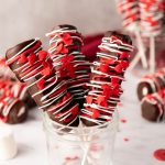 three marhsmallow pops in a glass cup