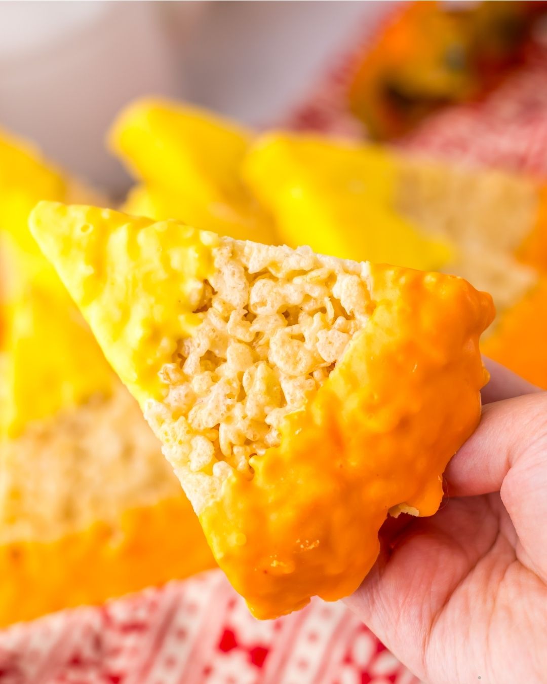 a hand holding a candy corn decorated rice krispie treat