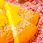 triangle shaped rick krispie treat with the top dipped in yellow chocolate and bottom is dipped in orange chocolate